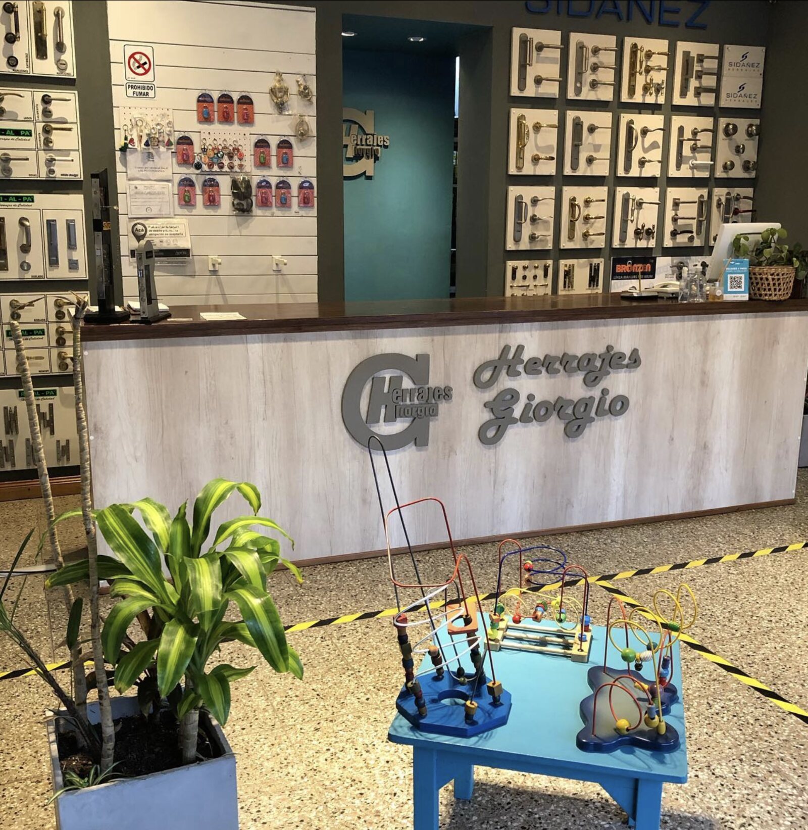 Interior del showroom de Herrajes Giorgio: paneles con manijas y cerraduras, mostrador con el logo